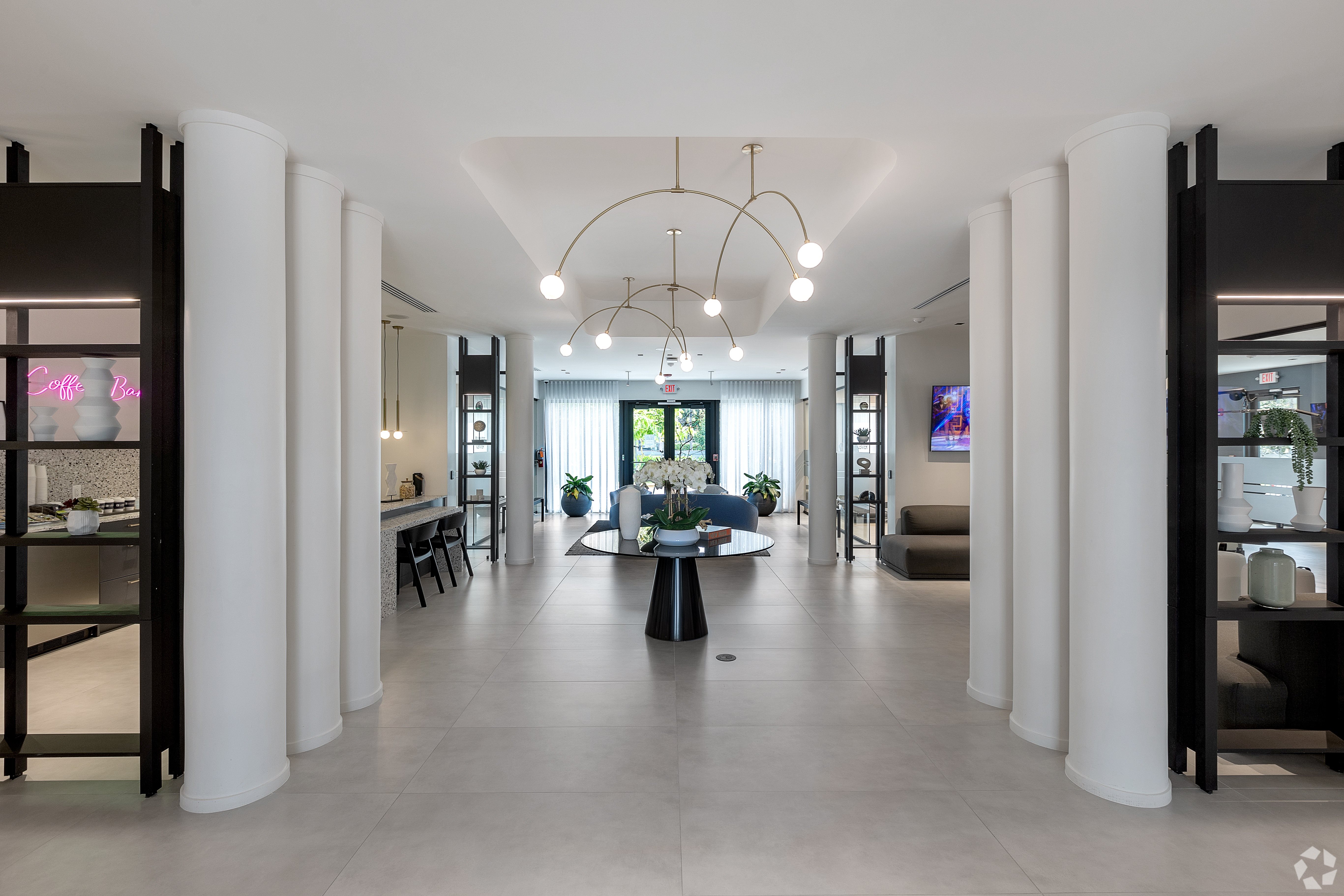 A spacious hallway with white columns and a black floor.